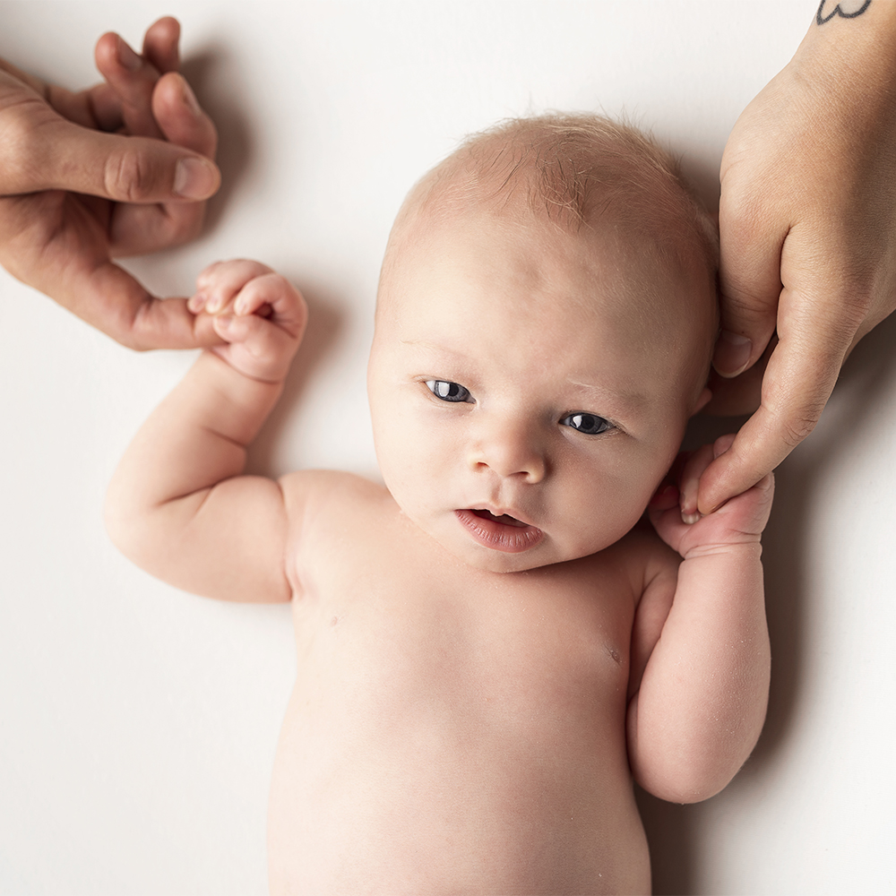 nyfödd bebis håller i föräldrarnas fingrar på nyföddfotogrfering i örebro